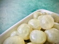 Peeled fresh longan in a white diamond bowl on a green background. Close up view. Royalty Free Stock Photo