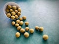 Longan in white bowl, poured out on green background. Royalty Free Stock Photo