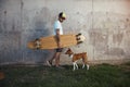 Longboarder with basenji dog next to gray concrete wall Royalty Free Stock Photo