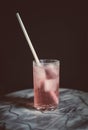 Longdrink glass with white straw in rose coloured cocktai