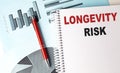 LONGEVITY RISK text on a notebook with pen on a chart background Royalty Free Stock Photo