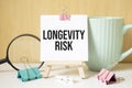 LONGEVITY RISK text written on black notebook with magnifying glass and a pen. Business and achievement concept