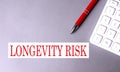 LONGEVITY RISK text written on a gray background with pen and calculator