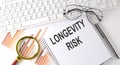 LONGEVITY RISK text written on a notebook with keyboard, chart,and glasses Royalty Free Stock Photo