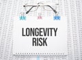 LONGEVITY RISK text written on paper with pen and glasses