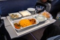 Inflight airplane Asian food set meal served consisting rice and spicy chicken, appetizer, dessert, bun and red wine Royalty Free Stock Photo