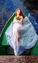 Longing, beautiful sensual, seductive, young sexy redhead woman with a with a bouquet of wilted flowers lying in a boat in lake Royalty Free Stock Photo