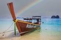 Longtail boat on beach in Thailand with rainbow