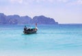 Longtail boat sailing on the tropical andaman sea with small limestone island background