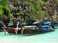 Longtale boats at the Phuket beach with limestone rock on background in Thailand. Phuket island is a most popular tourist destinat