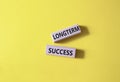 Longterm success symbol. Wooden blocks with words Longterm success. Beautiful yellow background. Business and Longterm success Royalty Free Stock Photo