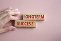 Longterm success symbol. Wooden blocks with words Longterm success. Businessman hand. Beautiful pink background. Business and Royalty Free Stock Photo