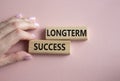 Longterm success symbol. Wooden blocks with words Longterm success. Businessman hand. Beautiful pink background. Business and Royalty Free Stock Photo