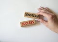 Longterm success symbol. Wooden blocks with words Longterm success. Businessman hand. Beautiful white background. Business and Royalty Free Stock Photo