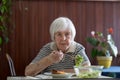 Lonley solitary elderly woman having lunch alone sitting at the table at home. Lonely late life period of a widow. Royalty Free Stock Photo