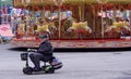 Bank Holiday Weekend Fairground ride and man on mobility scooter