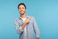 Look at ads here! Portrait of handsome happy man in stylish denim shirt pointing aside, showing copy space Royalty Free Stock Photo