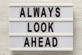 `Always look ahead` words on a modern board, clipboard with blank sheet of paper on a white wooden background, top view. Overhea