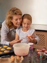 Those look amazing, honey. a little girl decorating cupcakes with the help of her grandmother.