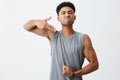 Look at this body. Portrait of young dark-skinned serious man with afro hairstyle showing gun gesture with hand