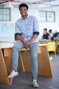 The look of confidence. Full lenght portrait of a handsome young businessman sitting on a desk in his office. Royalty Free Stock Photo