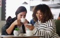 Look at the cute message he just sent me. two young women looking at something on a cellphone in a cafe. Royalty Free Stock Photo