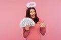 Look at this! Excited happy woman with brown hair and halo over head pointing finger at dollar bills in her hand, surprised with Royalty Free Stock Photo