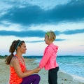 Mother and daughter on seacoast in evening having fun time