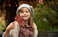 Look how beautiful it is. Portrait of a cute little girl holding an autumn leaf shes found in the garden.