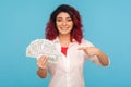 Look, I`m rich! Portrait of successful happy woman with fancy red hair pointing to dollar bills