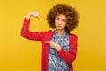 Look, I`m strong! Portrait of confident woman with curly hair raising arm pointing biceps as metaphor of power