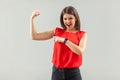 Look, I am strong and independent! Portrait of happy beautiful brunette young woman in red shirt standing, looking, pointing and Royalty Free Stock Photo