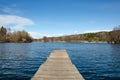 A look from a lonely pier on the blue expanse of a large lake on a warm spring day.