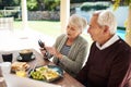 Look at the message I just got. an affectionate senior couple using a cellphone while enjoying a meal together outdoors. Royalty Free Stock Photo