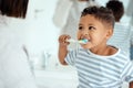 Look mom, I got every tooth. an adorable little boy brushing his teeth while his mother helps him at home. Royalty Free Stock Photo