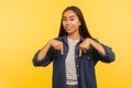 Look, nice advertise here! Portrait of happy pretty girl in denim shirt pointing down place for commercial text