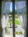 Look out through an old wooden window in a swiss farm house with white lace curtains Royalty Free Stock Photo