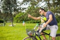Look over there. Active family day in nature. Father and son ride bike through city park on sunny summer day. A cute boy