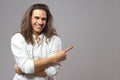 Look over there. Handsome cheerful man with long hair shows ad