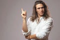 Look over there. Handsome confident man with long hair shows ad Royalty Free Stock Photo