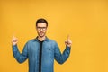 Look over there! Happy young bearded handsome man in casual pointing away up and smiling while standing isolated over yellow Royalty Free Stock Photo