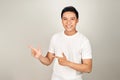 Look over there! Happy young handsome man in basic clothing pointing away and smiling while standing against white background Royalty Free Stock Photo