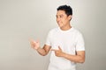 Look over there! Happy young handsome man in basic clothing pointing away and smiling while standing against white background Royalty Free Stock Photo