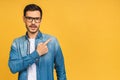 Look over there! Happy young handsome man in casual pointing away at copyspace and smiling while standing isolated over yellow Royalty Free Stock Photo