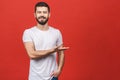 Look over there! Happy young handsome man in casual pointing away and smiling while standing against red background Royalty Free Stock Photo