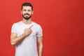 Look over there! Happy young handsome man in casual pointing away and smiling while standing against red background Royalty Free Stock Photo