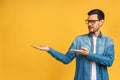 Happy young handsome man in casual pointing away and smiling while standing isolated over yellow background Royalty Free Stock Photo