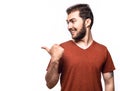 Look over there. Smiling boy in studio. Handsome cheerful man with short hair and beard shows advertisement. Space for your text Royalty Free Stock Photo