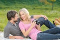 Look at this photo! Loving young couple is looking at the photographs they made on a picnic