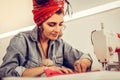 Beautiful woman sewing a dress sitting at desk. Royalty Free Stock Photo